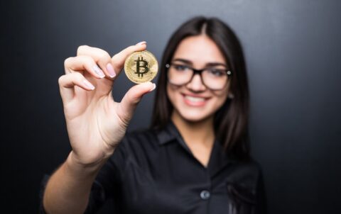 young-successful-confident-woman-with-glasses-holds-gold-bitcoin-her-hand-isolated-black-wall_231208-11715